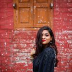 Charming woman in traditional attire posing against a rustic brick wall, showcasing elegance and cultural heritage.